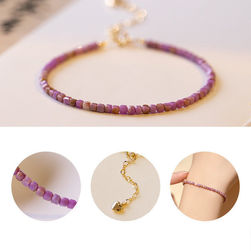 Close-up of small cubic lilac crystal beads and gold heart charm
