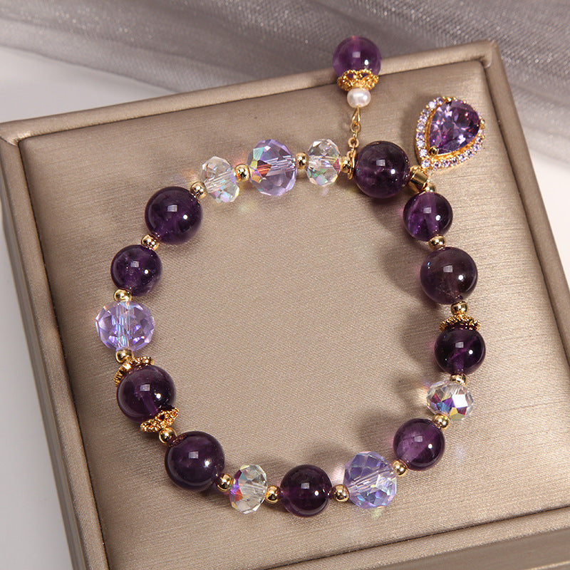 Elegant Amethyst crystal bracelet with sparkling charms on a golden display
