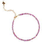 Close-up of small cubic lilac crystal beads and gold heart charm