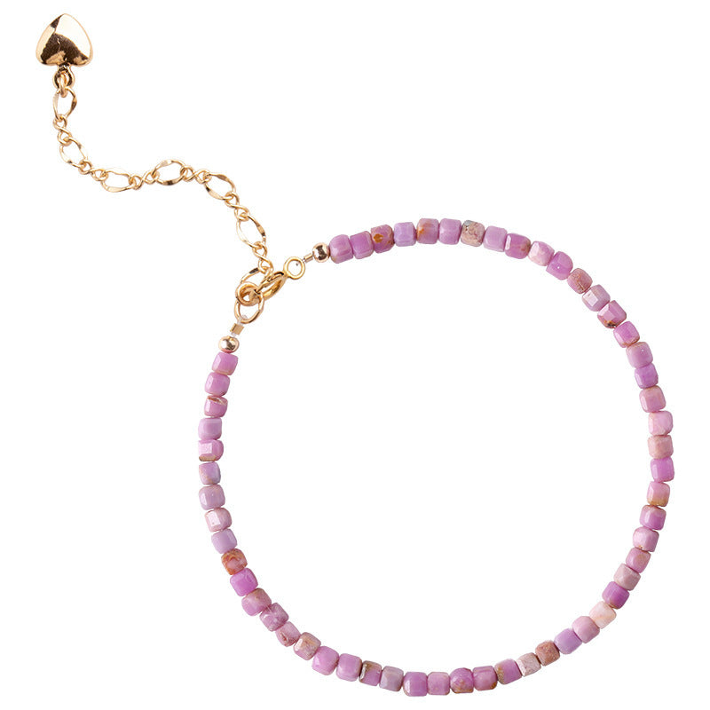 Close-up of small cubic lilac crystal beads and gold heart charm